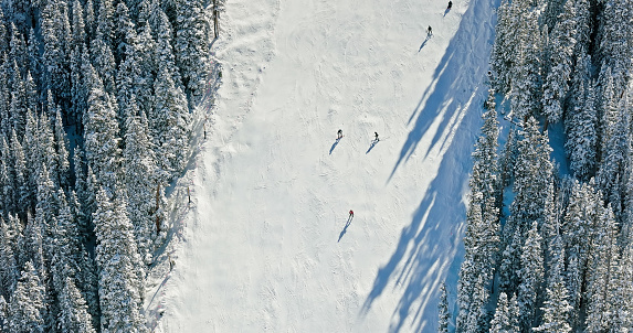 Aerial still image of people skiing and snowboarding down a hill at a ski resort on a cold, sunny morning near Loveland Pass, Dillon, Colorado.