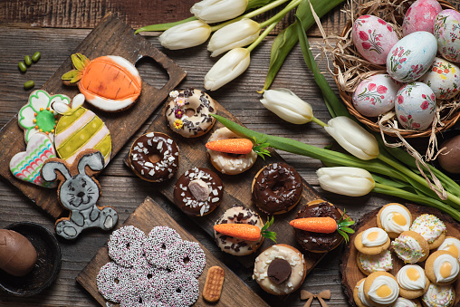 Festive table with colorful Easter decoration, Easter eggs, flowers and delicious sweet biscuits