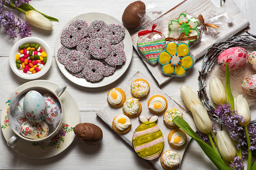 Festive table with colorful Easter decoration, Easter eggs, flowers and delicious sweet biscuits