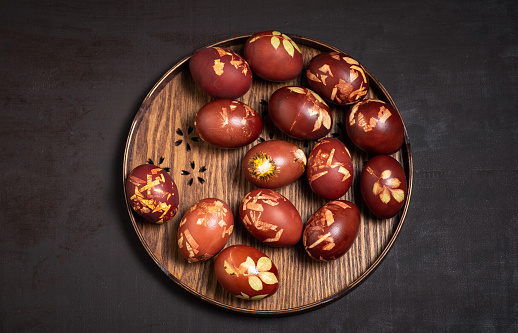 Easter eggs dyed with onion peel in a wooden bowl on a dark wooden background