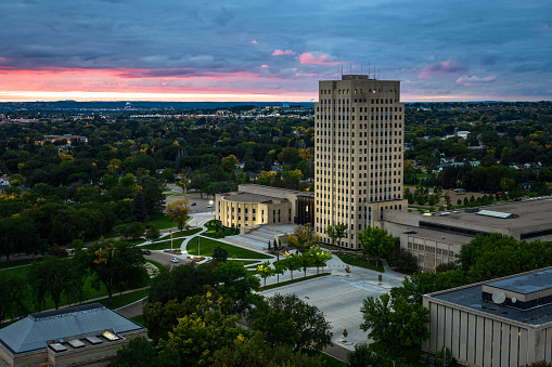 Aerial view of the North Dakota State Capitol building in Bismarck, the capital city of North Dakota, on a dramatic overcast sunset with a red tinted sky in Fall.\n\nAuthorization was obtained from the FAA for this operation in restricted airspace.