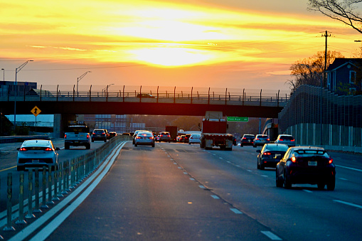Vienna, Virginia, USA - November 20, 2023: A brilliant sunset illuminates the sky as commuters travel westbound during rush hour on Interstate 66 in Northern Virginia.