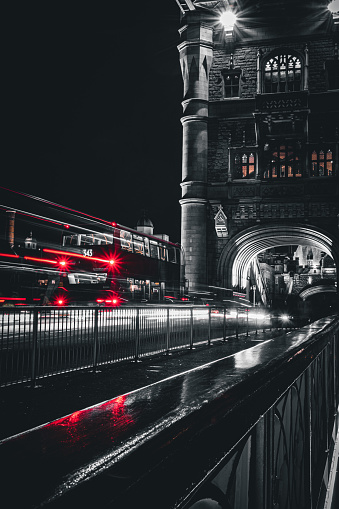 A black, white and red long exposure shot of a bus on the Tower Bridge in London