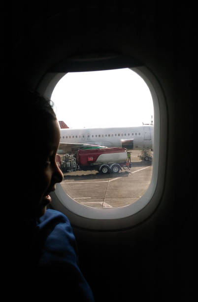 Asian kid on the window seat of a plane.