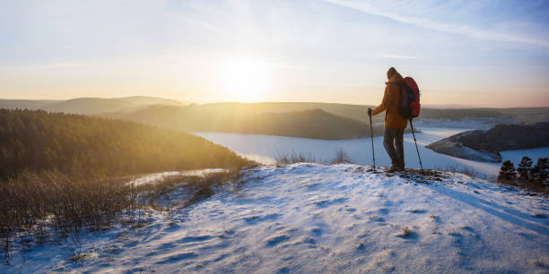 istock Man with backpack walking up a hill at sunset.  Winter hiking. Banner with copy space. 1812485333