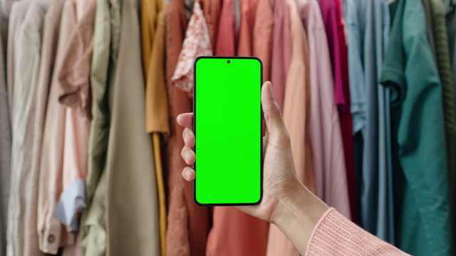 Fashion, app and hand with phone and green screen for online shopping, clothes and promotion. Mobile, application and person with social media display on smartphone for mockup with clothing in store