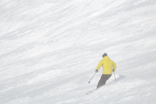 A single male 68 year-old skier skiing on empty ski slop, Hokkaido, Japan