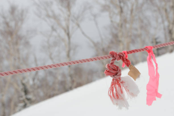 pink ribbon hanging on faded red rope by knot