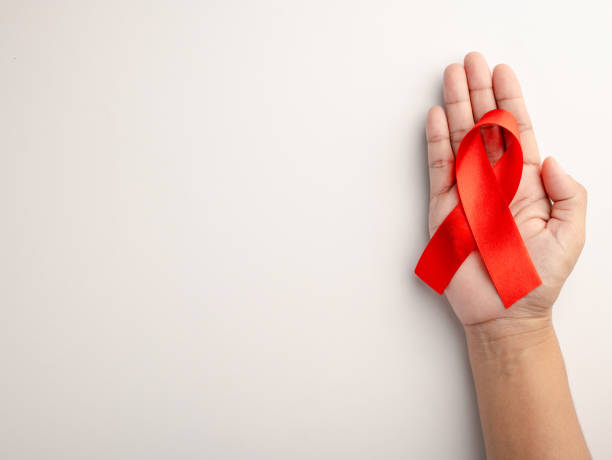 istock AIDS ribbon in hand isolated on white background 1812548218