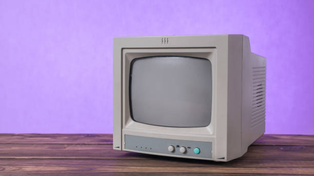 istock A small retro TV on a wooden table on a lilac background. 1812611742