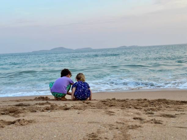 istock Crouched brother and sister together at the beach 1812622933