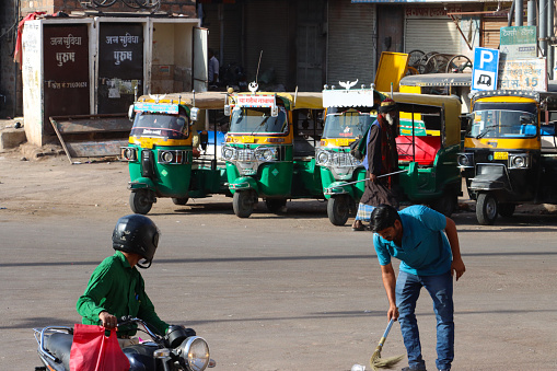 New Delhi, India - April 12, 2023: Stock photo showing close-up view of a rank of parked green and yellow and black auto rickshaws waiting for tourist fares.