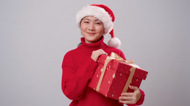 Asian woman happy smiling showing a gift box to camera, standing isolated over white background.