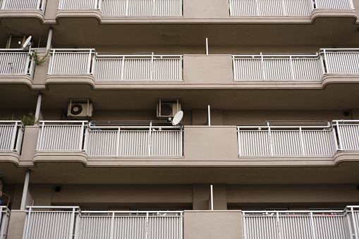 Looking up at an old building with air conditioners and satellite dishes on the balconies.