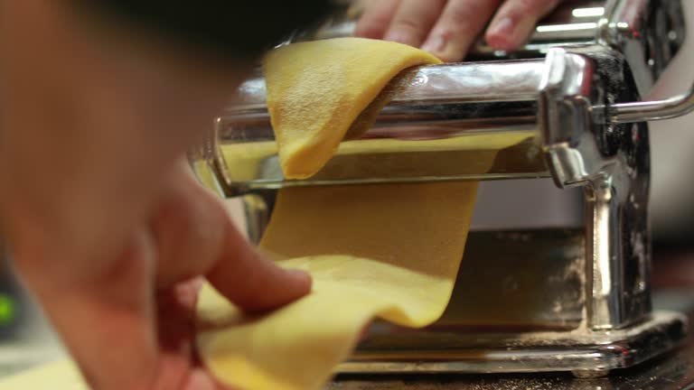 Using a pasta machine, the chef prepares pasta by hand.