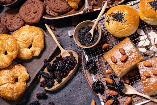 Table top view of organic rustic style bakery with whole grain bun, bread and cookies with various berry and nut for homemade healthy pastry and traditional baking bread