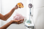 Woman pouring shower gel on bath sponge