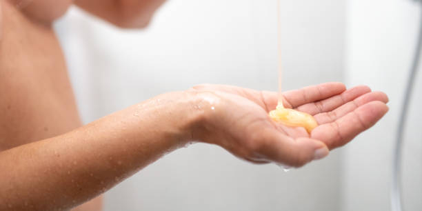 Woman pouring shower gel in hand close up Woman pouring shower gel in hand while showering close up hair care women mature adult human skin stock pictures, royalty-free photos & images