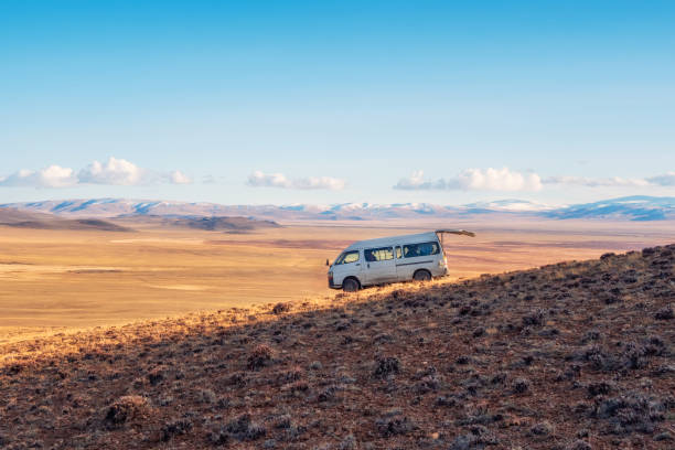 istock An old white van with an open rear trunk, parked on a steep mountain slope against the background of the autumn steppe, an extreme journey through the vast expanses. 1812835070