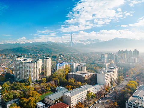 Aerial view of Almaty city with Television Tower during sunny day with snow capped mountains