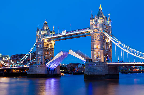 Tower Bridge at Dusk in London Tower Bridge opening up ready to let a ship pass underneath. opening bridge stock pictures, royalty-free photos & images