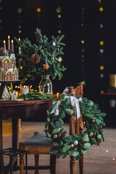 istock Christmas wreath with natural elements, decorated with eucalyptus , pine cones, oranges. Holiday atmosphere, festive mood. Wooden vintage furniture, cozy interior, fir tree on background 1812869014