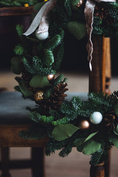 istock Christmas wreath with natural elements, decorated with eucalyptus , pine cones, oranges. Holiday atmosphere, festive mood. Wooden vintage furniture, cozy interior, fir tree on background 1812870597