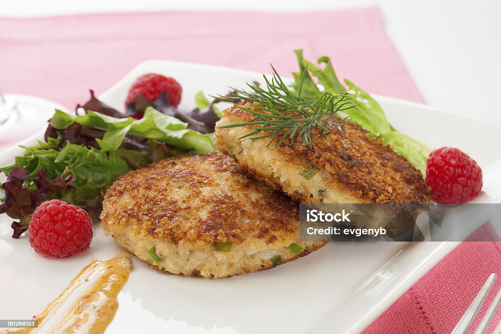 Crab Cakes Two crab cakes appetizer garnished with spicy sauce, green salad, and raspberry. Appetizer Stock Photo