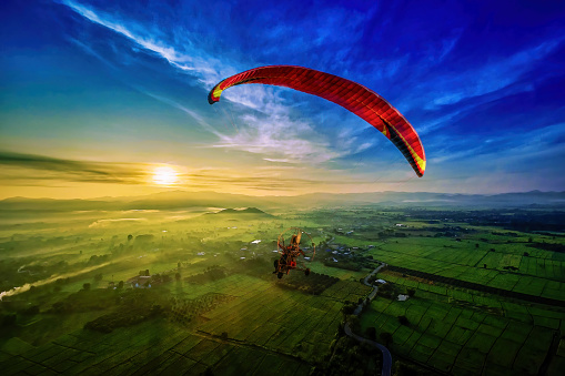 Flying with paramotor in the blue sky - Man riding paramotor in the blue sky background
