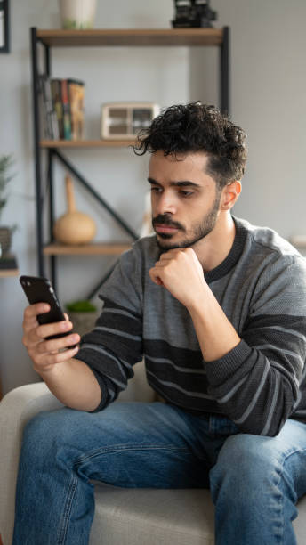 istock Young man looks bored at home and uses smartphone 1812883272