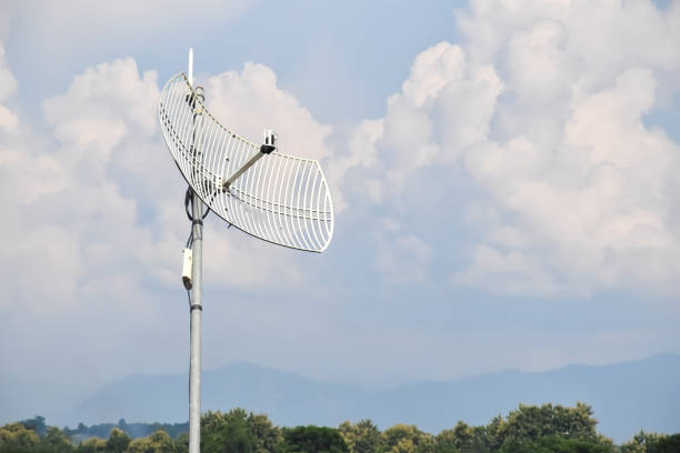 Internet wireless wifi receiver and repeater installed on metal pole on the roof of the building to service internet to users in local village, soft and selective focus.