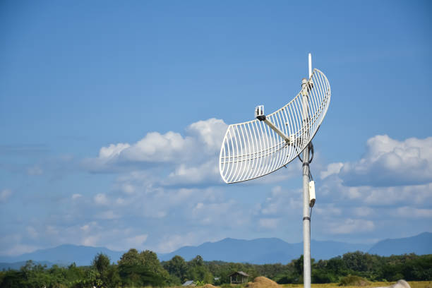 Internet wireless wifi receiver and repeater installed on metal pole on the roof of the building to service internet to users in local village, soft and selective focus.