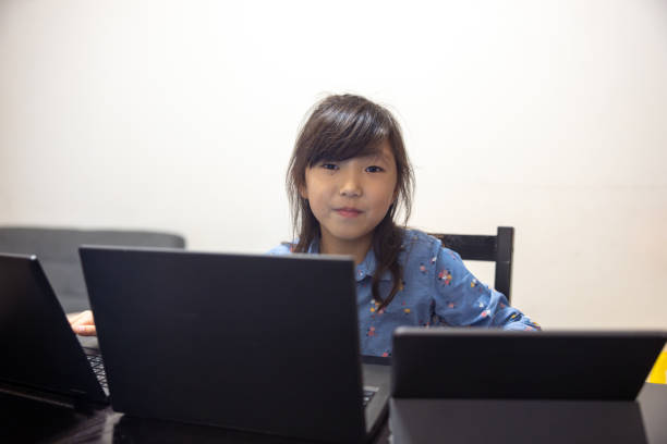 Portrait of little girl using multiple laptop devices at home