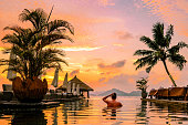 young men in swimming pool during sunset, Luxury swimming pool in tropical resor