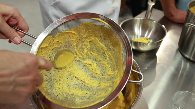 A professional chef works with a sieve and a spoon