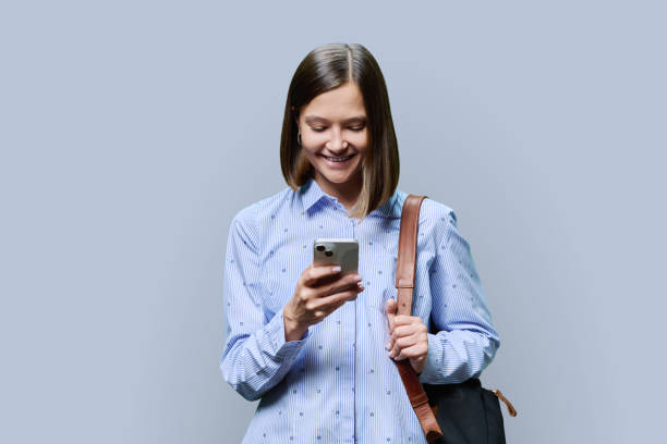 istock Young woman student with smartphone backpack on grey studio background 1812966160