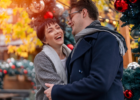 Handsome man and beautiful woman hugging each other as they walk around city, having a fun time, lifestyle photo