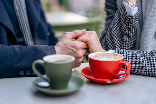 Handsome man and beautiful woman hugging each other as they walk around city, drinking coffee, tea, sitting in side cafe,    having a fun time, lifestyle photo