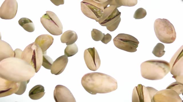 Close-up of salted pistachios flying on a white background
