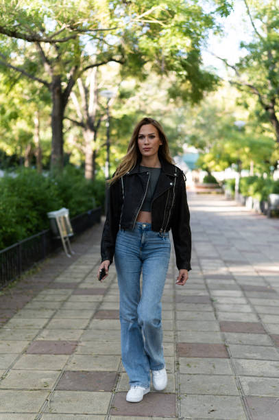 istock woman using phone walking along an urban park 1813030452