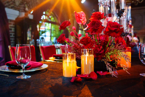 Beautiful festive table setting with fresh red flowers, napkins and candles.