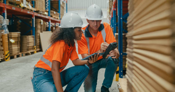 Young African American black woman and caucasian man warehouse worker checks stock and check merchandise package using barcode scanner in factory warehouse. Logistic industry business concept. joven mujer negra afroamericana y hombre caucásico trabajador de almacén verifica las existencias y verifica el paquete de mercancías utilizando un escáner de código de barras en el almacén de la fábrica. negocio de la industria logística.