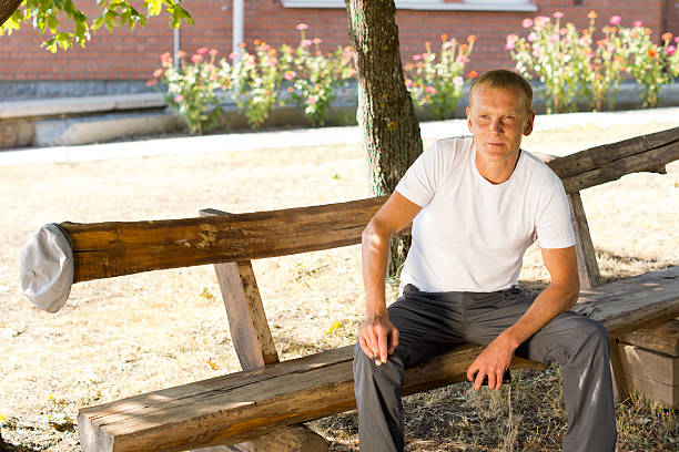istock Single man sitting lonely on a wooden bench 181306877