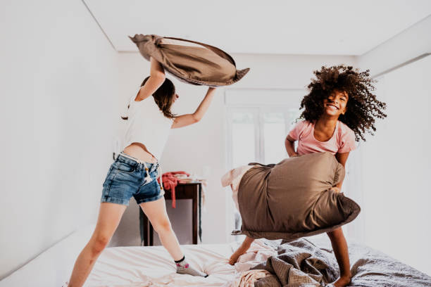 istock Girls playing pillow fight at home 1813070429