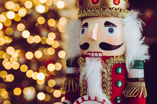 Traditional Christmas nutcracker wooden figure. Beautiful, festive toy soldier, winter holiday season decoration, with tree lights bokeh in background.
