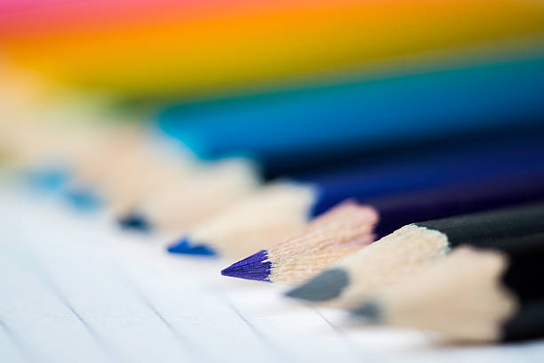Line of coloured pencils on lined paper stock photo