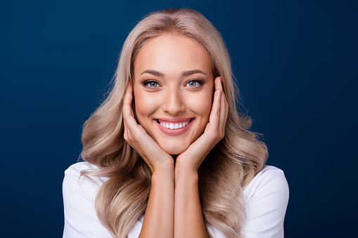 Close up photo of lovely pretty good mood girl two arms touch perfect clear skin face isolated on dark blue color background.