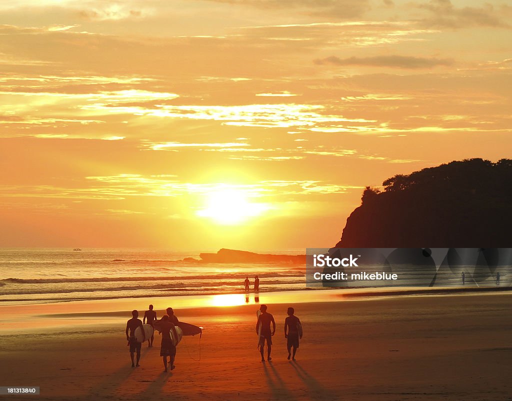 Surfers and beach goers gaze at the golden orange sunset  Surfers head out for last waves San Juan Del Sur Stock Photo