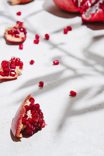 Aerial close up view of grains of pomegranate and fruit in a bowl and a white tasting spoon on the wooden table and brown cloth.  Natural vitamin supplement for a healthy diet