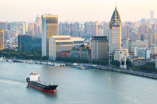 Aerial shot of cargo ship crossing the Huangpu River in Shanghai with modern buildings in the background, Shanghai is key to China's domestic and foreign trade